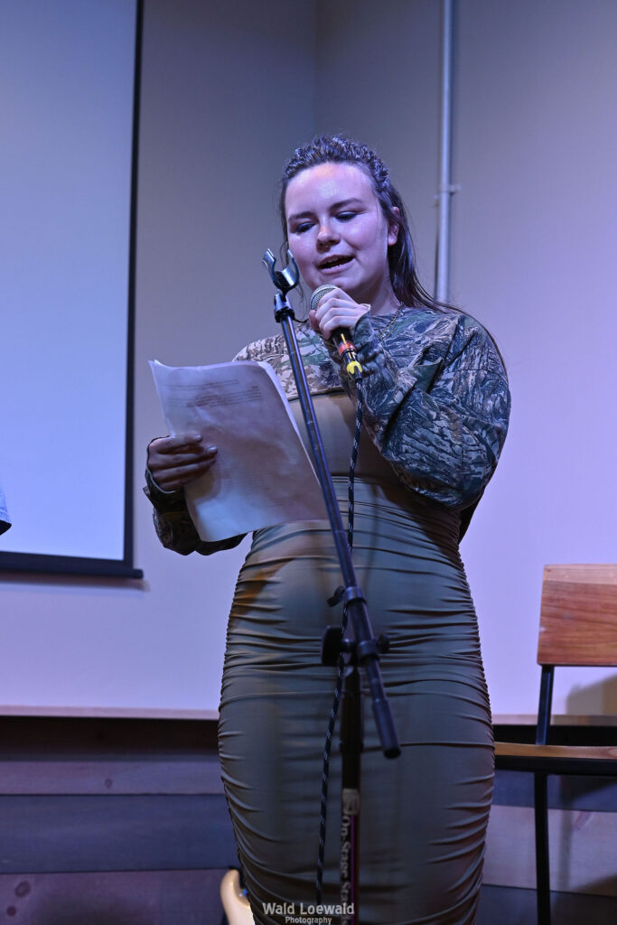 Esme, MadFreedom Advocates staff, standing on stage with mic