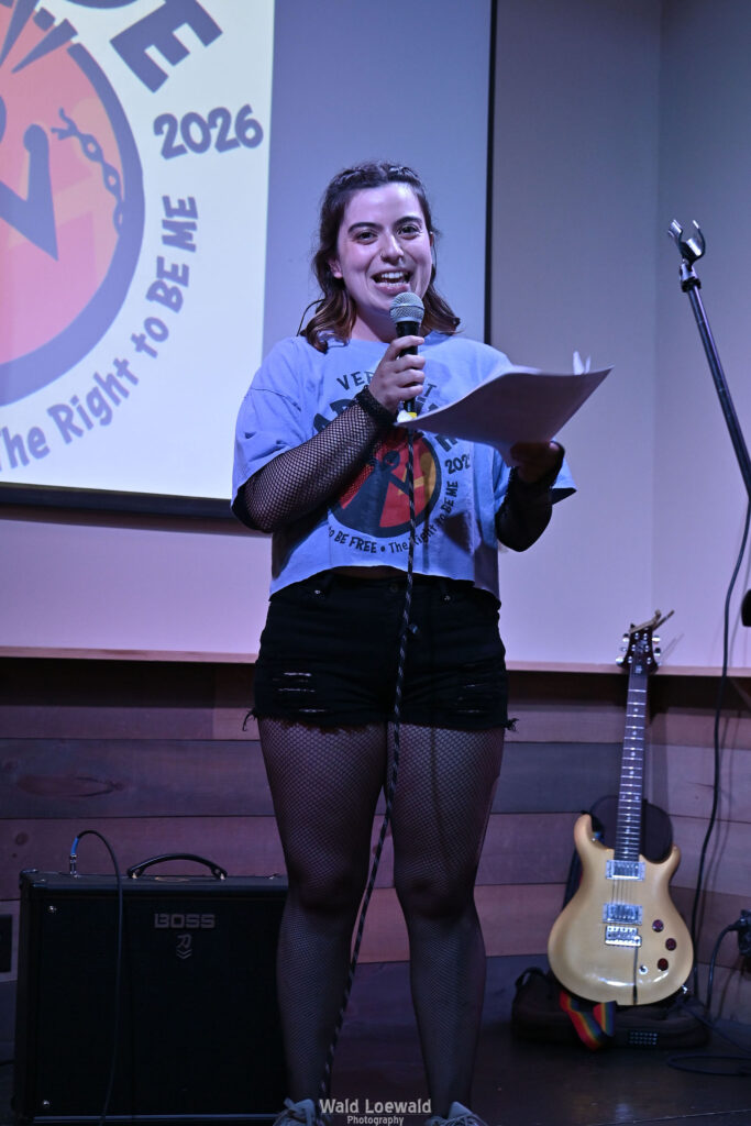 Neilah, MadFreedom Advocates staff, standing on stage with mic in front of Mad Pride 2026 logo