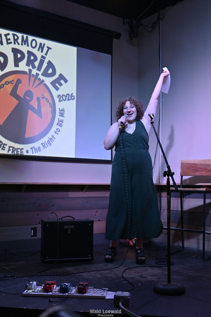 Performer behind a mic in front of the Mad Pride 2026 logo