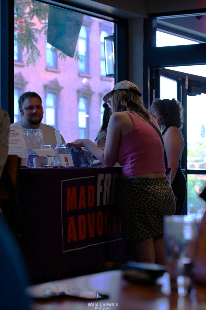 Volunteers and attendees standing at the MadFreedom Advocates table