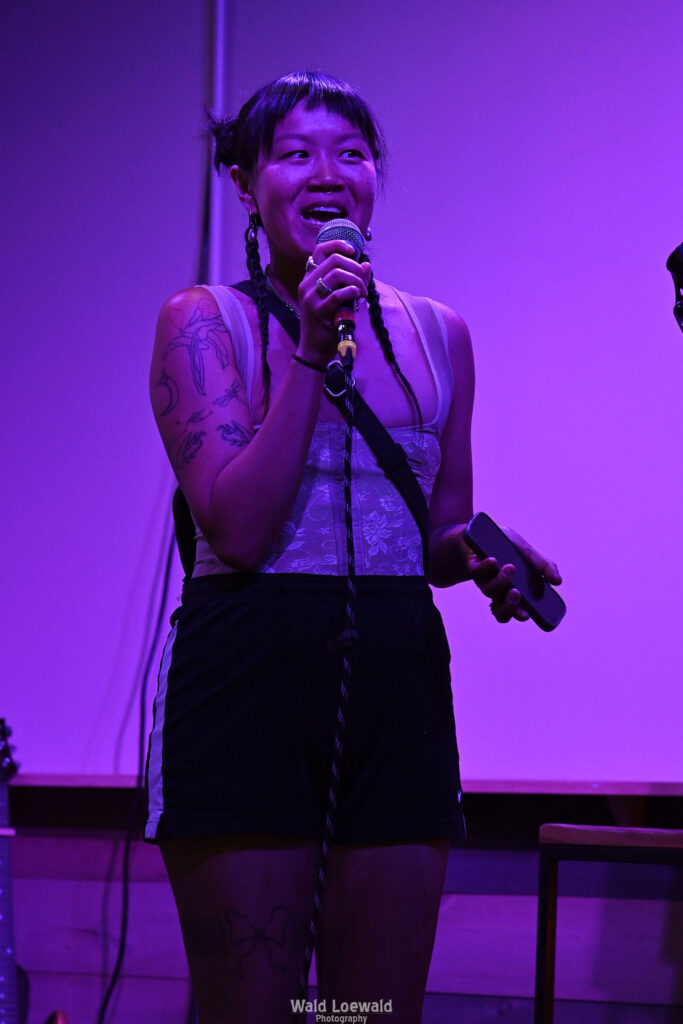 Performer on stage with mic in pink lighting