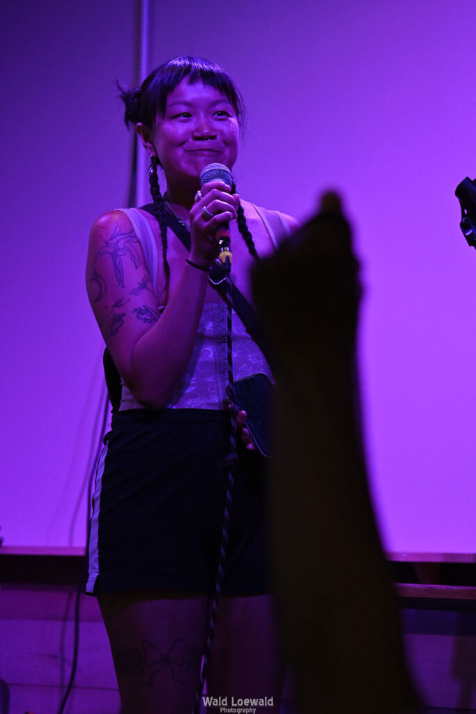 Performer on stage with mic in pink lighting