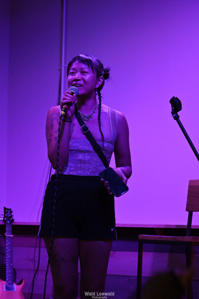 Performer on stage with mic in pink lighting