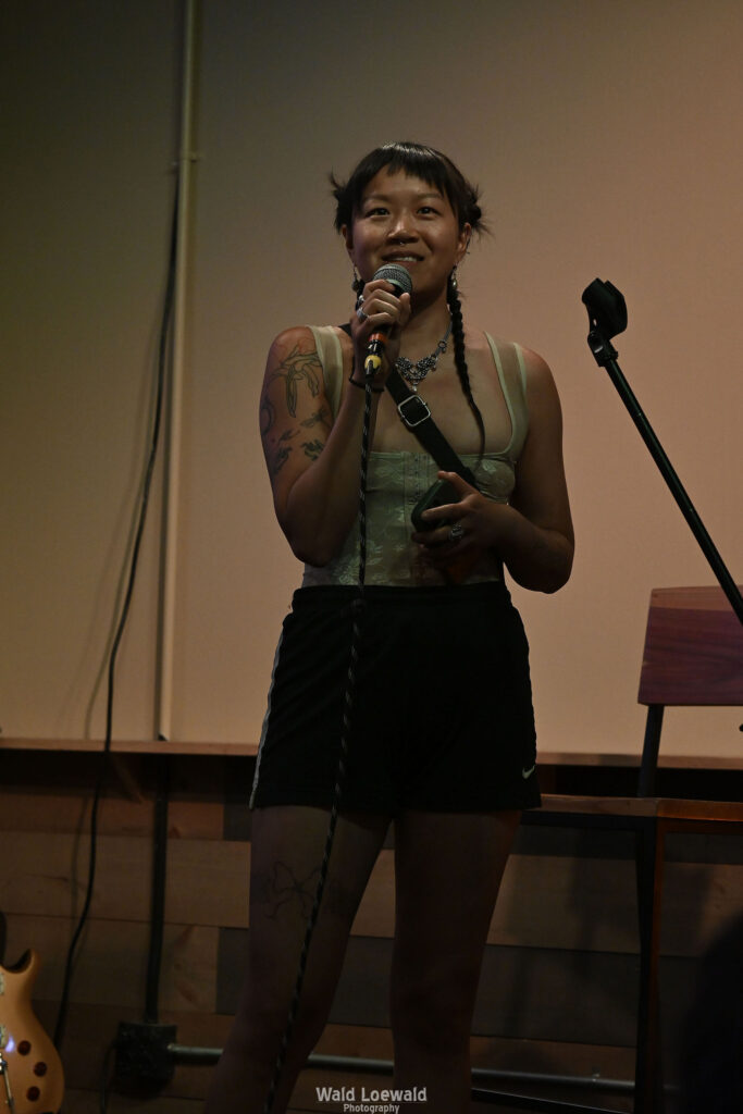 Performer on stage with mic in front of Mad Pride 2026 logo
