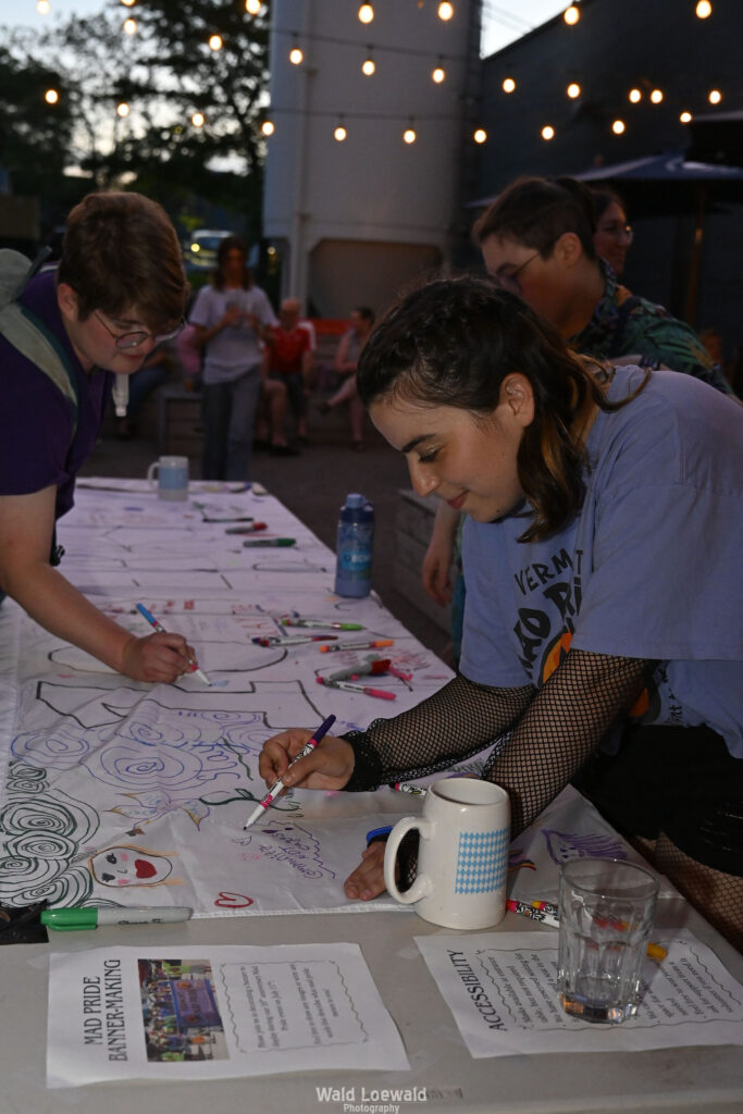 People signing white banner with colored markers