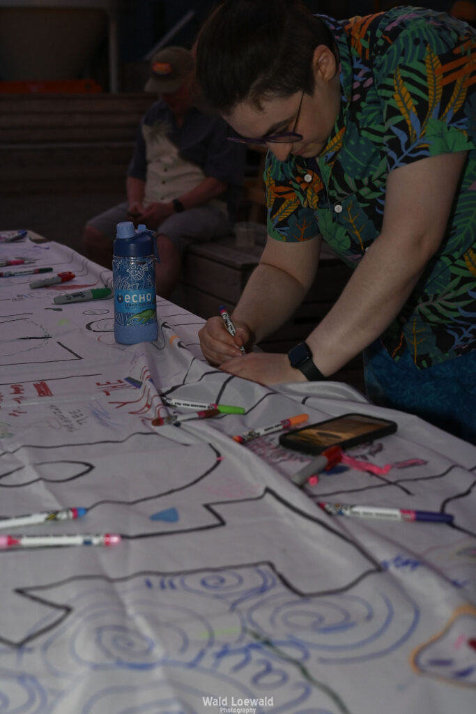 White banner that says 10 years with markers and people signing with color