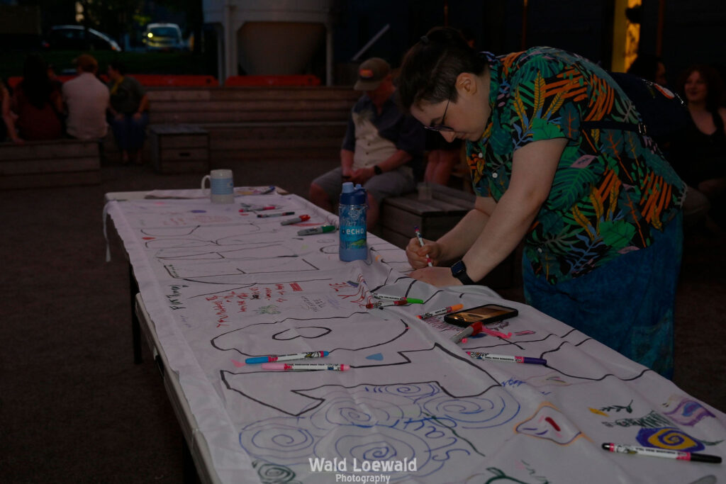 White banner that says 10 years with markers and people signing with color