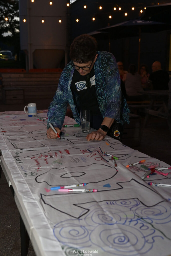 White banner that says 10 years with markers and people signing with color