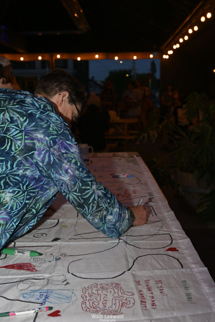 White banner that says 10 years with markers and people signing with color