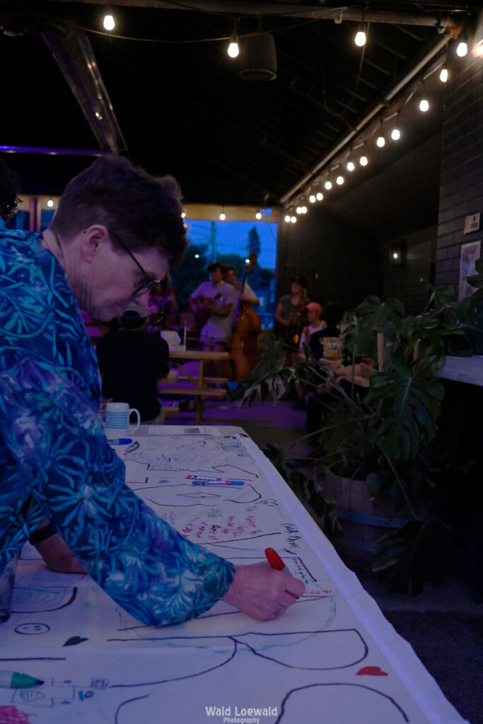 White banner that says 10 years with markers and people signing with color