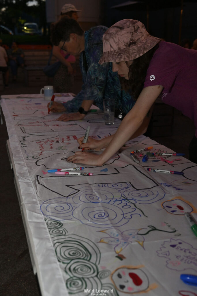 White banner that says 10 years with markers and people signing with color