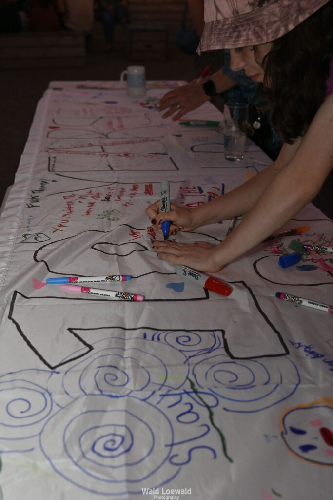 White banner that says 10 years with markers and people signing with color