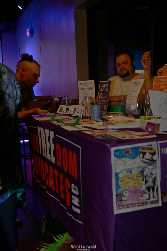 People surrounding MadFreedom Advocates table looking at materials