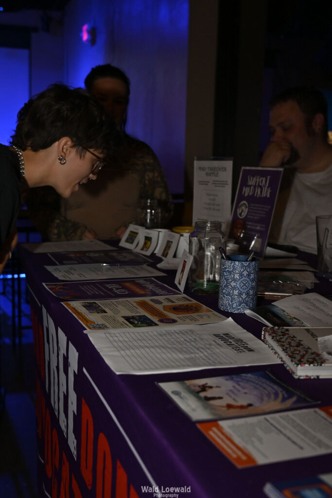 People surrounding MadFreedom Advocates table looking at materials