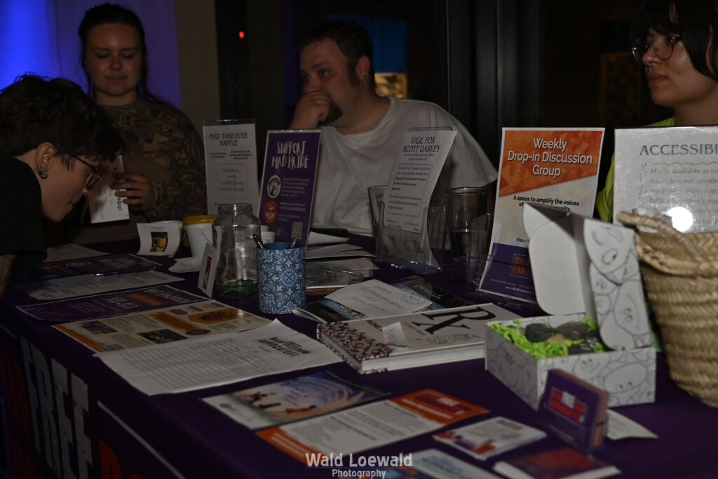 People surrounding MadFreedom Advocates table looking at materials
