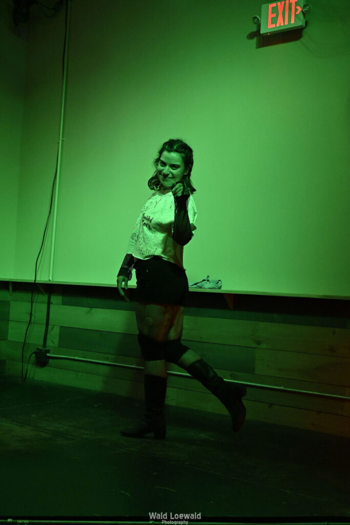Neilah in Mad Pride shirts performing in green lighting