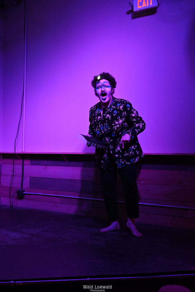 Performer on stage in costume in pink lighting